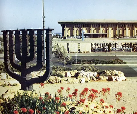 משכן הכנסת בירושלים בשנות ה-70, ובקדמת התמונה המנורה שמול הבניין.